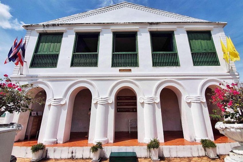 A white colonial-style building with green shutters, a balcony, and a flag. 5