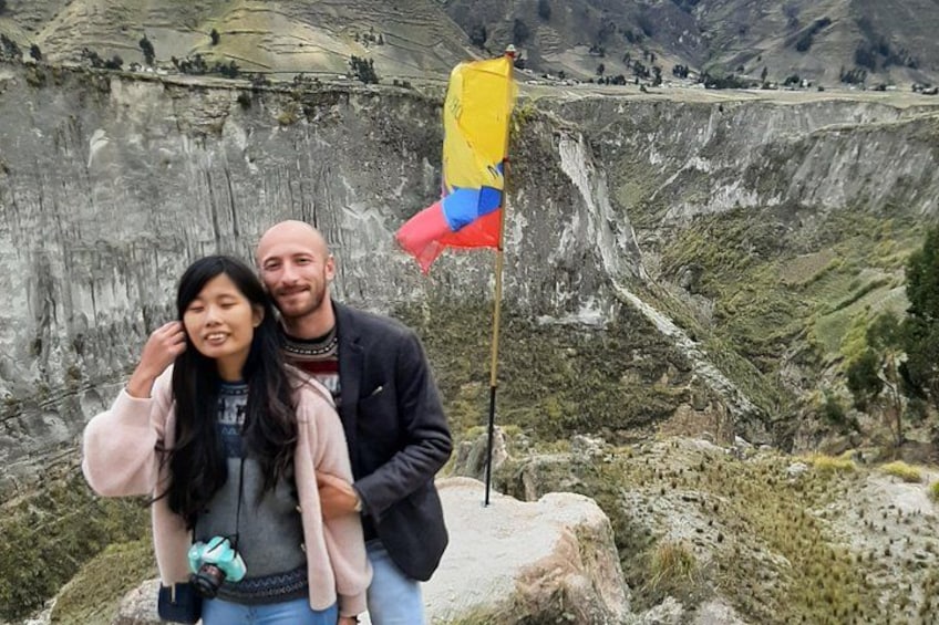 A couple standing in front of a large cliff with a flag. 3