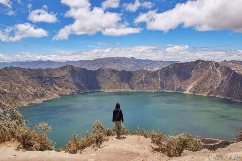 Una persona de pie en una colina con vistas a una amplia masa de agua rodeada de montañas. 1