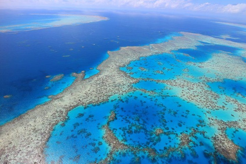 An aerial view of a coral reef system with clear blue waters and scattered islands. 4