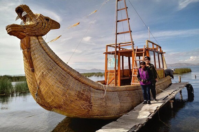 A traditional boat with a raised bow, docked at a pier. 1