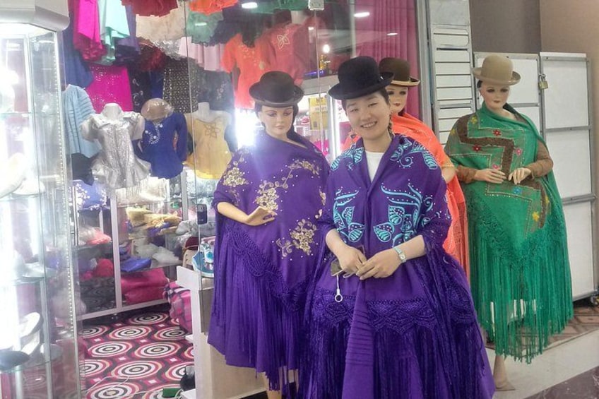 A store with mannequins dressed in traditional attire, a glass display case, and a patterned floor. 2