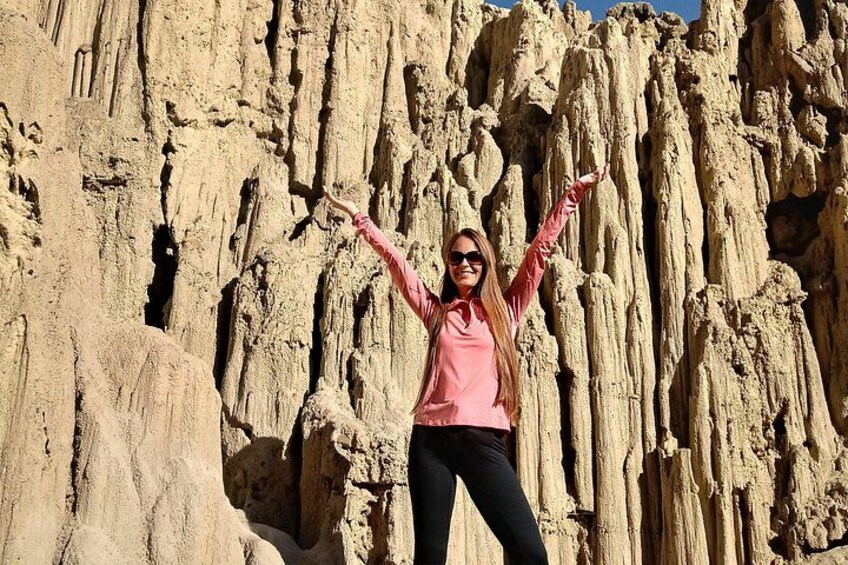 A person standing in front of a rocky cliff with arms raised. 5