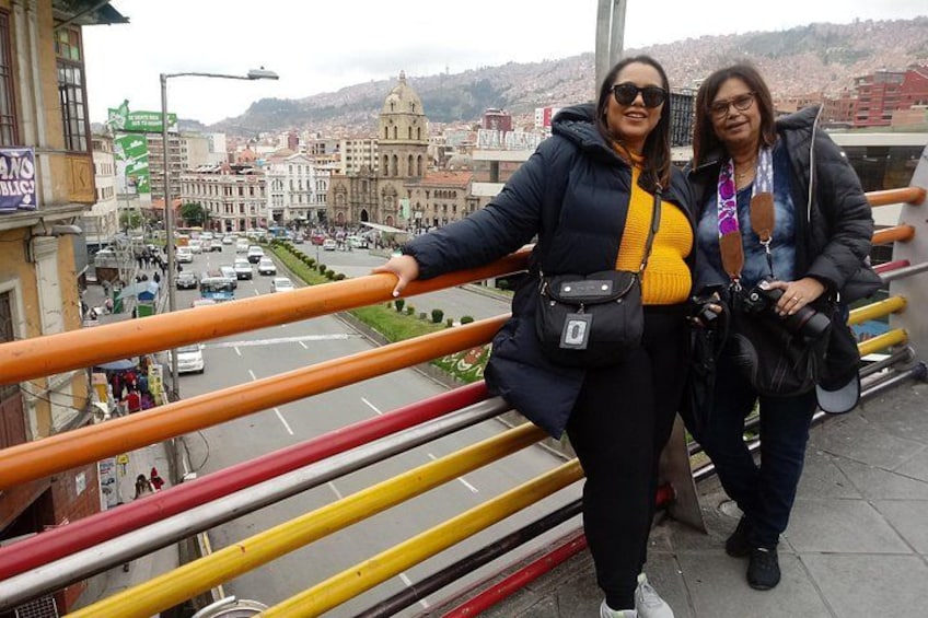 Two people standing on a bridge with a cityscape in the background. 4