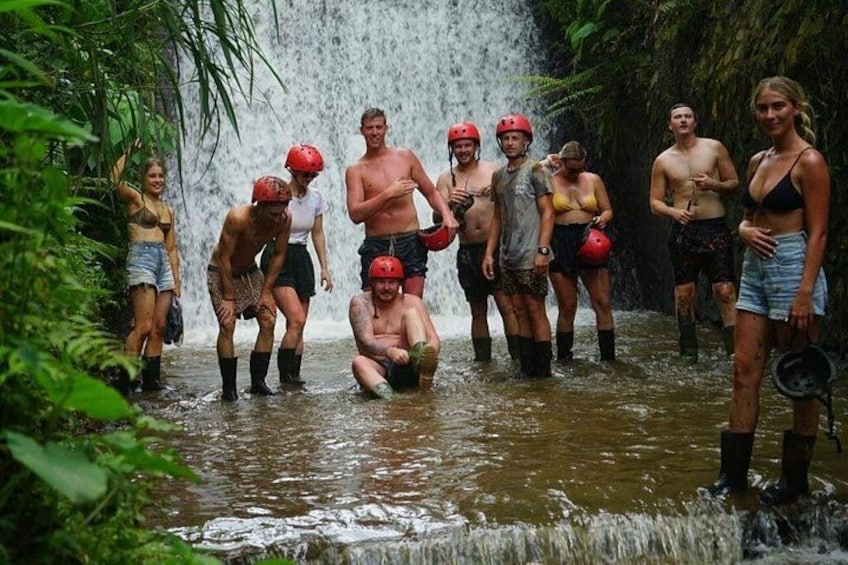 A group of people in a forested area with a waterfall. 4