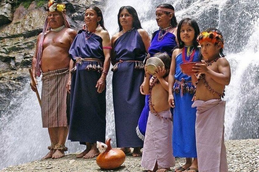 A group of people in traditional attire standing by a waterfall. 5
