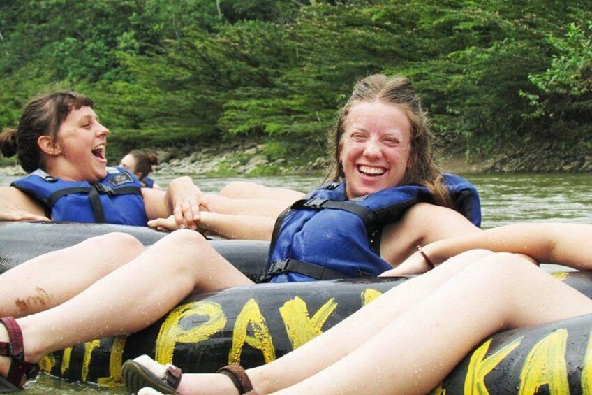 People on inflatable rafts on a river surrounded by greenery. 2