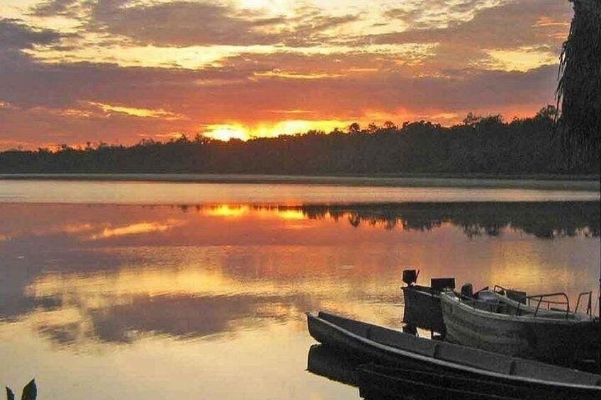 A calm lake at sunset with a boat docked on the right. 5