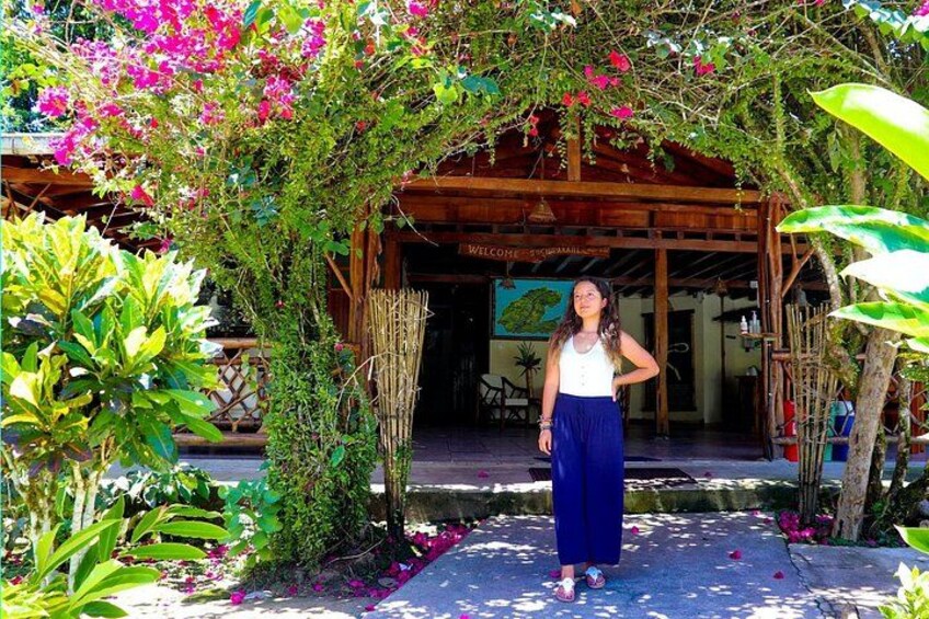 A person standing under a wooden pergola with pink flowers and greenery. 4
