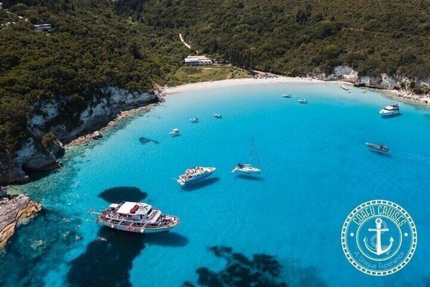 A coastal area with boats anchored in clear blue waters, surrounded by cliffs and a beach. 3
