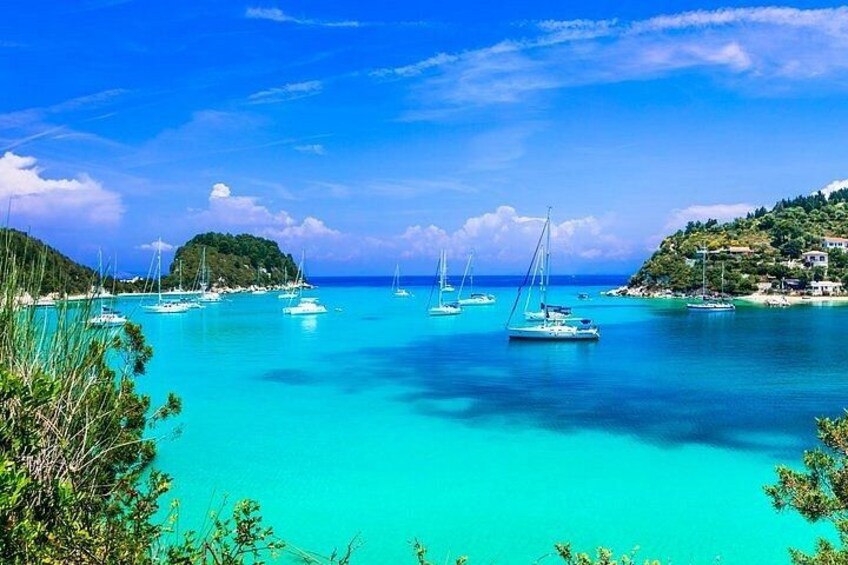 A turquoise sea with sailboats, a small island, and lush greenery. 4