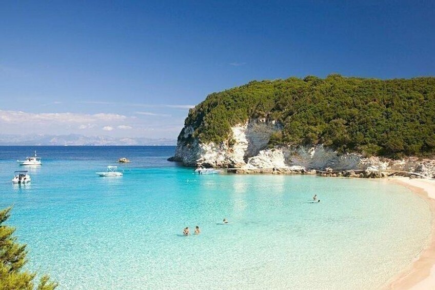 A beach with clear turquoise water, boats, and a rocky cliff. 5
