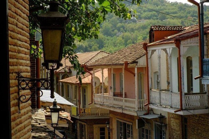 A narrow street with traditional buildings, a street lamp, and a view of a hillside. 4