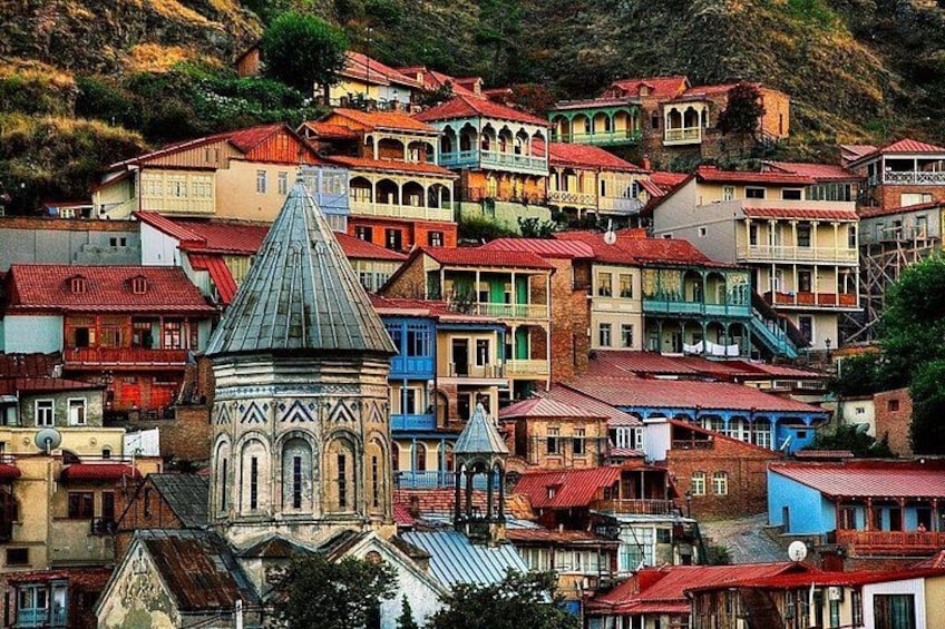 A colorful hillside town with a prominent church and tightly packed buildings. 1