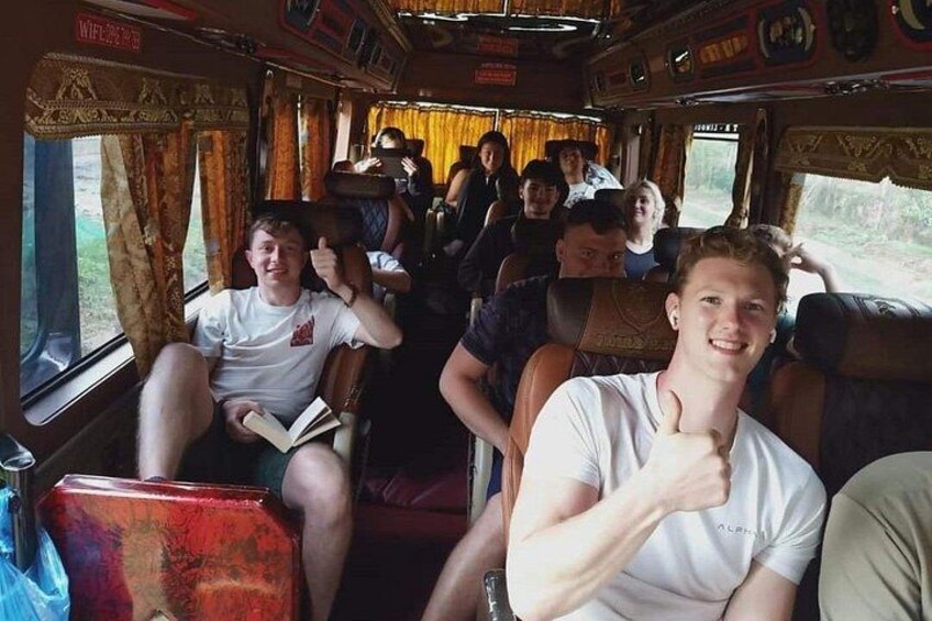 A bus interior with passengers seated, some reading and others using electronic devices. 4