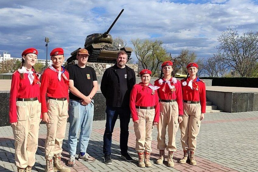 Un grupo de personas con uniformes rojos de pie frente a un tanque. 2