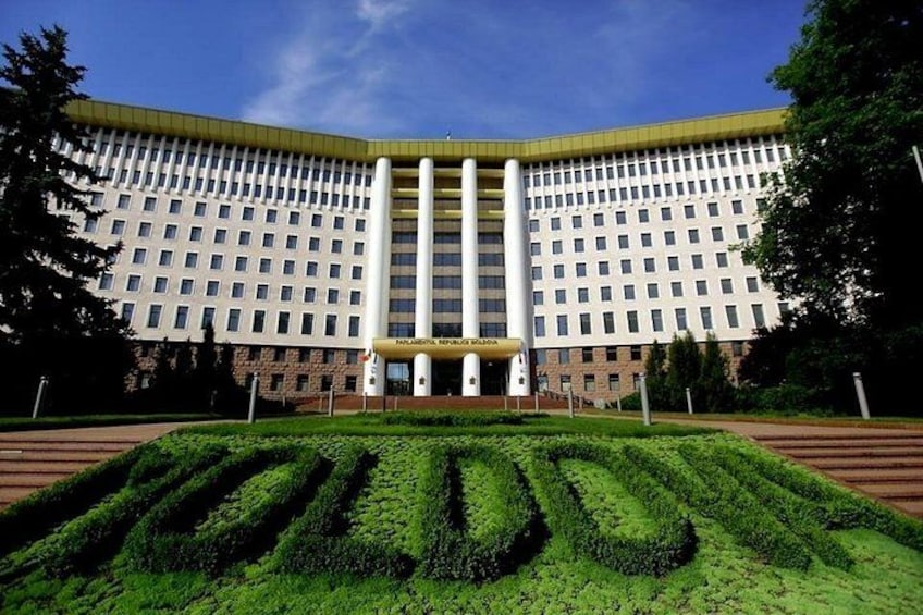 Un edificio grande e institucional con una fachada simétrica, una entrada central y un césped verde bien cuidado al frente. 3