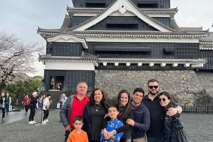 A group of people in front of a traditional Japanese building with a stone base and tiled roof. 5