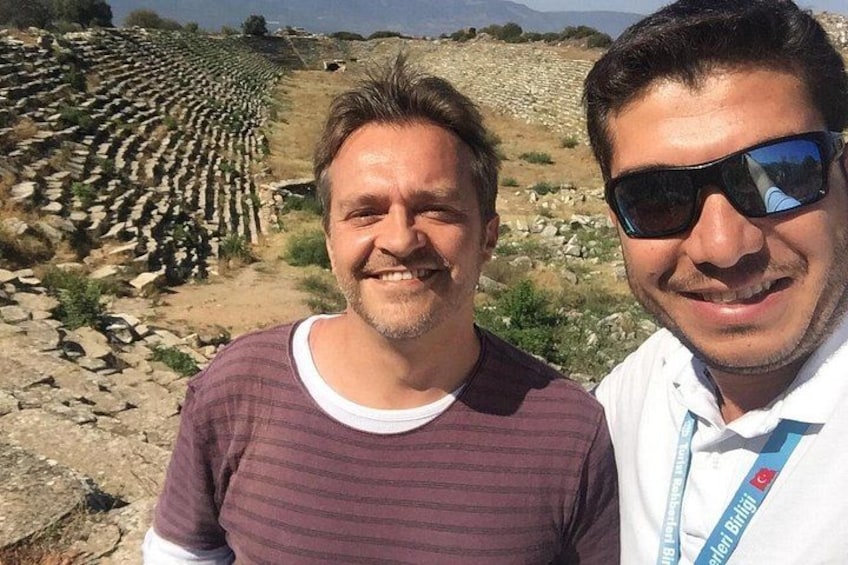 Two people standing in front of a stone wall with rows of stones. 4