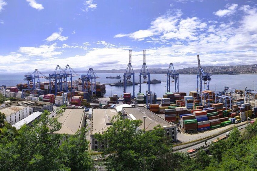 A port with shipping containers, cranes, and a body of water. 5