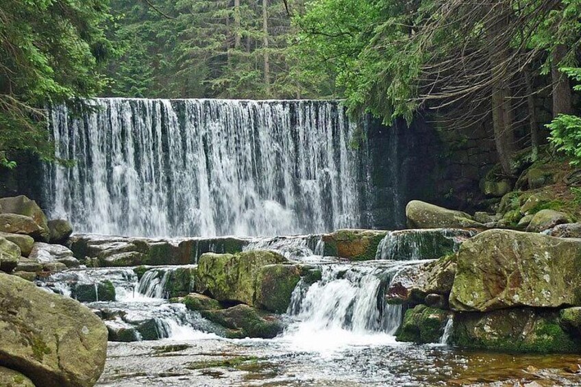 A waterfall surrounded by rocks and trees. 1