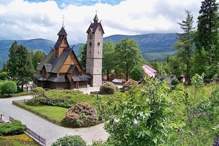 A church with a tall tower, surrounded by lush greenery and mountains in the background. 1