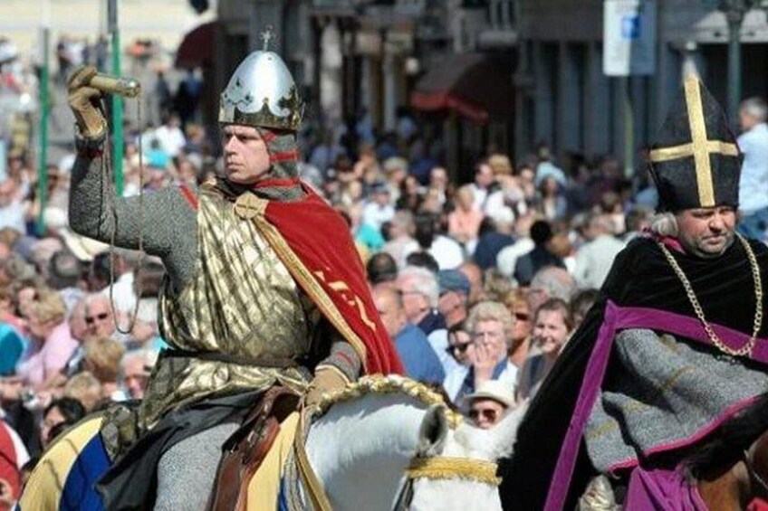 A person in medieval armor on horseback, another in religious attire, and a crowd in the background. 4