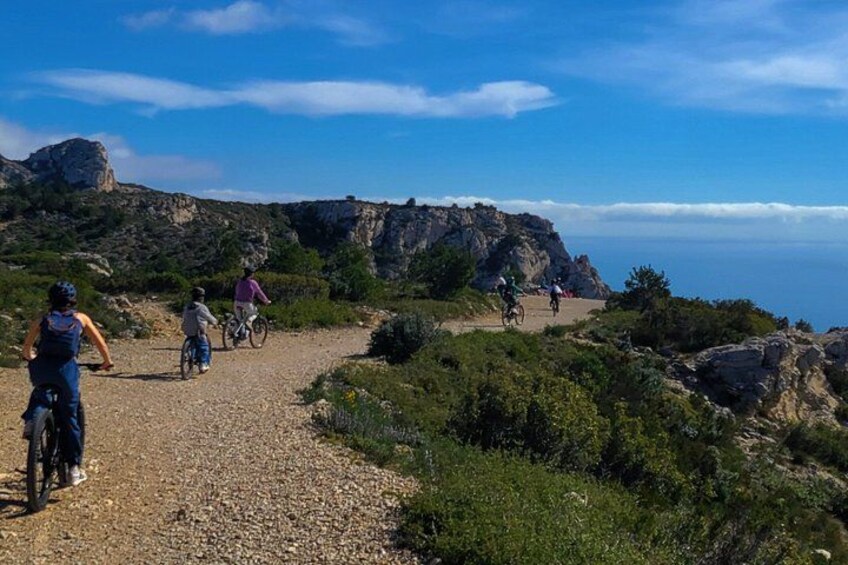 A gravel path with cyclists, rocky terrain, and a clear sky. 3