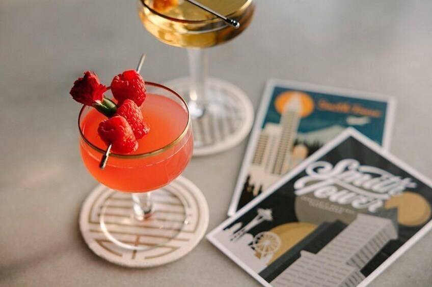 Een cocktailglas met een rode drank, versierd met aardbeien, en een onderzetter. Er liggen ook twee onderzetters en een tijdschrift op de tafel. 4