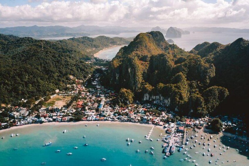 A coastal town with a beach, boats, and mountainous terrain. 2