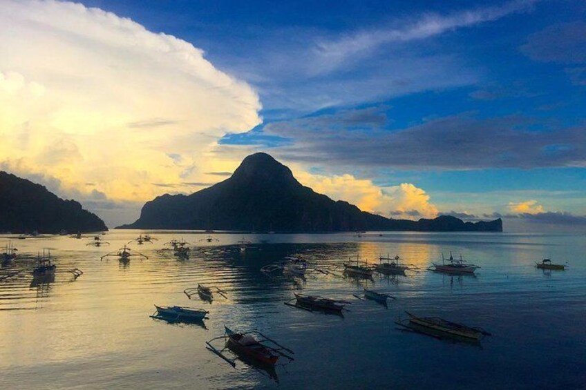 A calm sea with boats and a prominent mountain in the background. 4