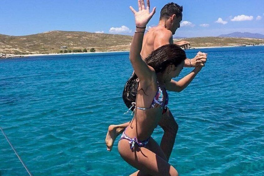 Una persona en traje de baño de pie en agua azul cristalina, con un paisaje montañoso al fondo. 2