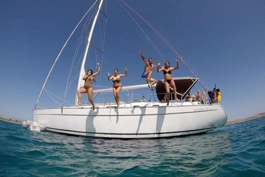 Un velero con personas en la cubierta, mar en calma y cielo despejado. 5