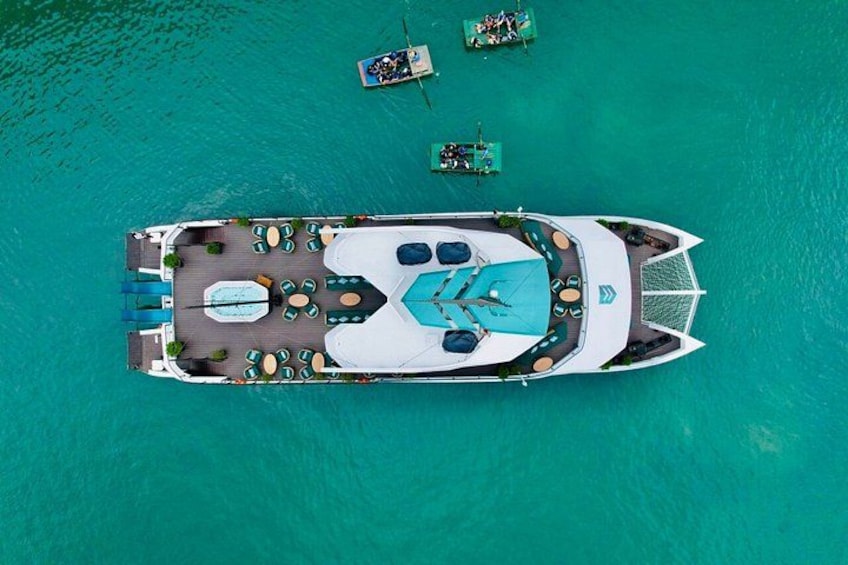 Un barco amarrado en aguas turquesas con terraza, sillas de descanso y piscina. 3