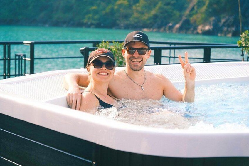 Una pareja en un jacuzzi con vistas panorámicas al agua y follaje en el fondo. 5
