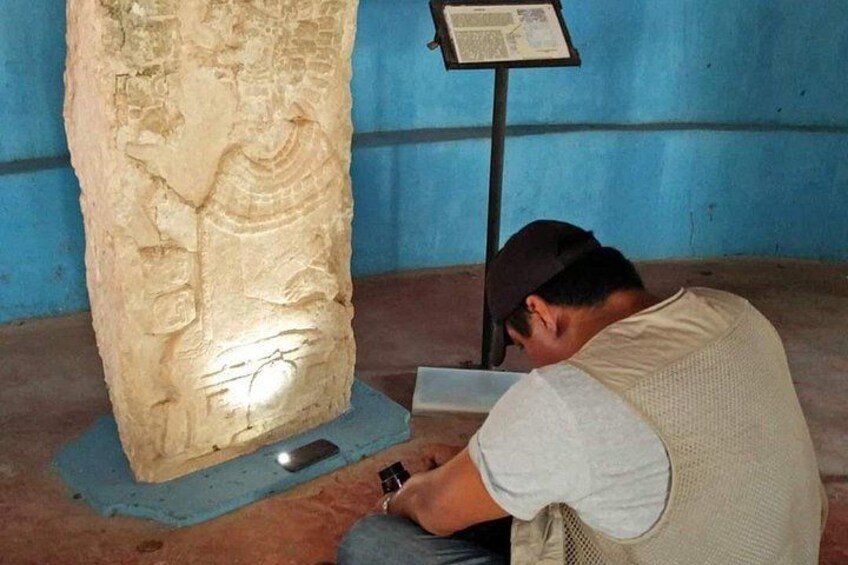 Une personne examine une grande sculpture en pierre ornée d’inscriptions. 3