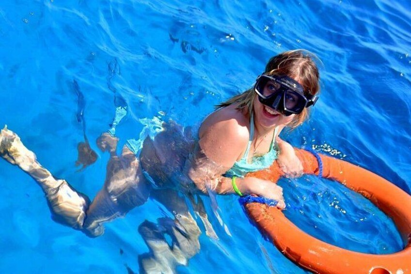 En person som flyter i en pool med hjälp av en orange flytanordning. 2