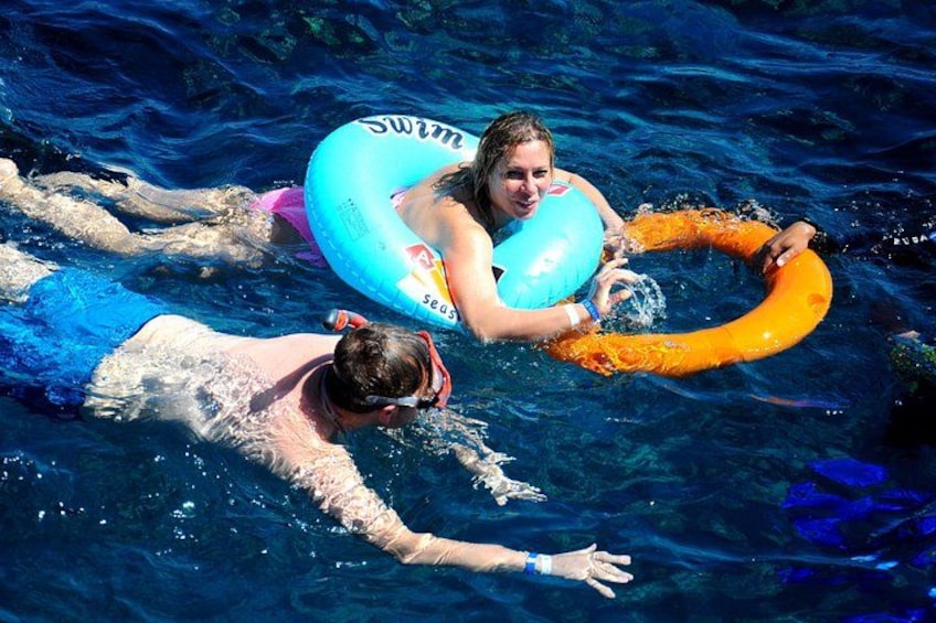 Two people swimming in a pool with inflatable rings. 1