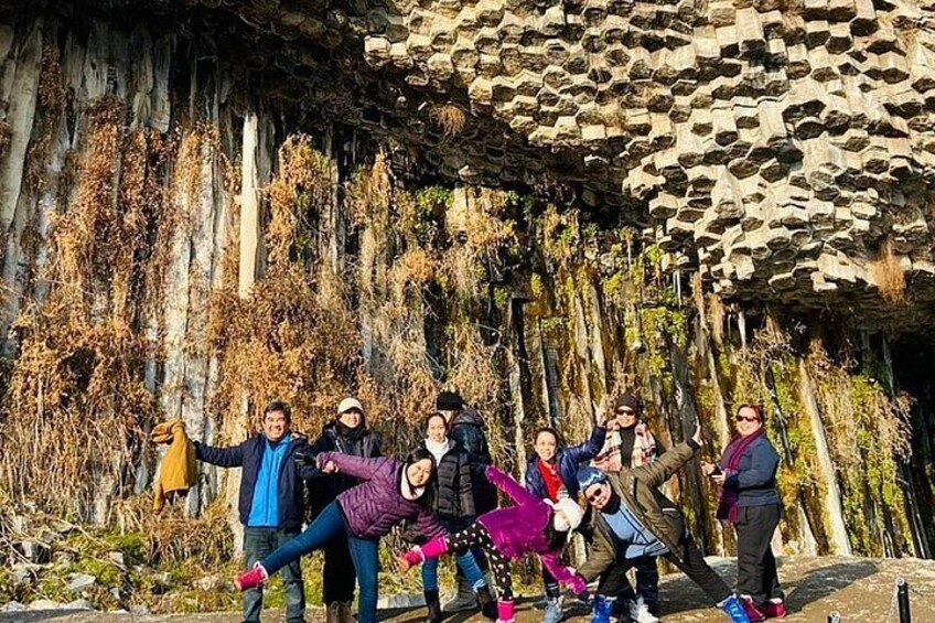 A group of people posing in front of a cave with stalactites. 5