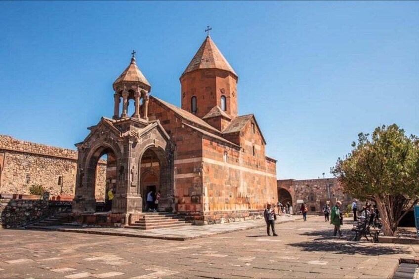 A historic church with a bell tower and arches, surrounded by a stone wall and a clear sky. 3