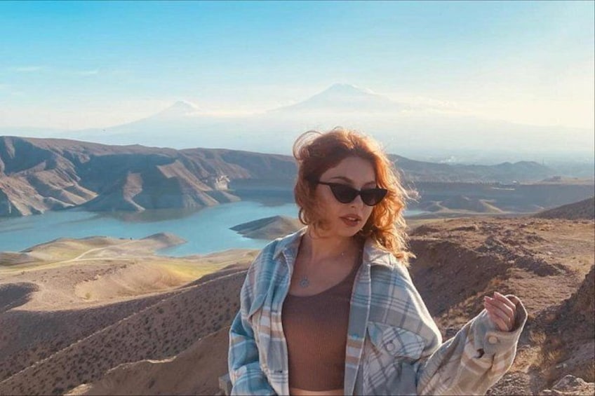 Eine Person steht auf einem Hügel und blickt auf ein Tal mit einem Berg im Hintergrund. 1