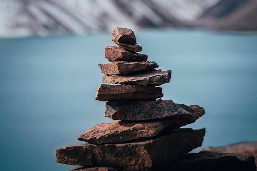 A stack of rocks by a body of water with mountains in the background. 2