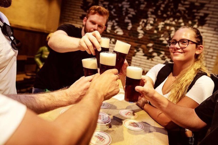People toasting with beer glasses at a table. 1