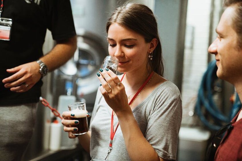 A person holding a glass of dark liquid, possibly a beverage, in a casual indoor setting. 4