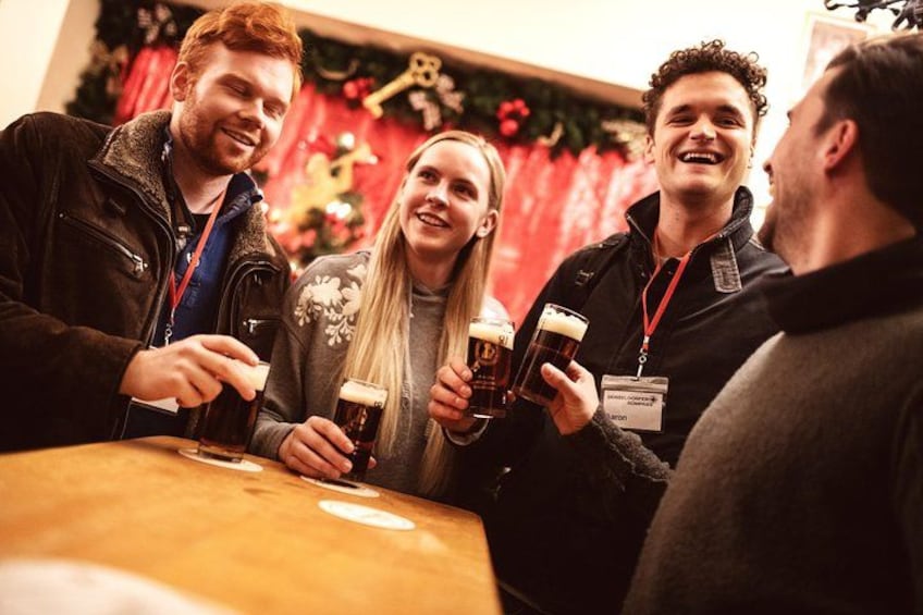 A group of people toasting with beer glasses at a table. 2
