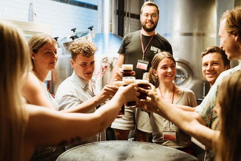 A group of people toasting with drinks around a table in a kitchen setting. 5