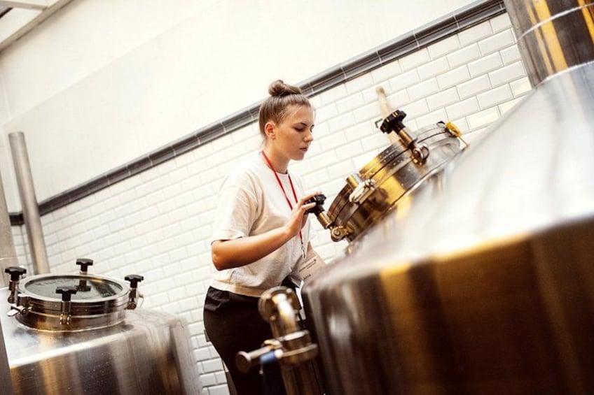 Iemand werkt met grote roestvrijstalen brouwketels in een brouwerij. 5