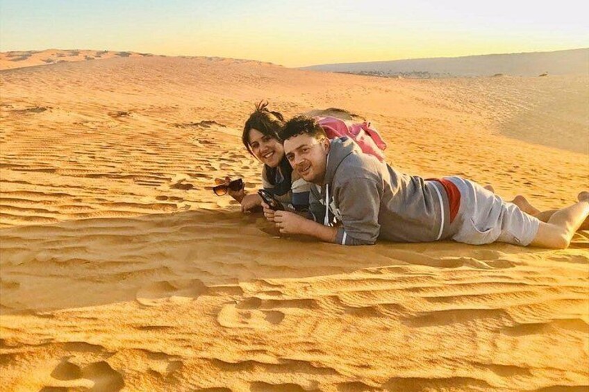 Two people lying on sand dunes in a desert landscape. 5