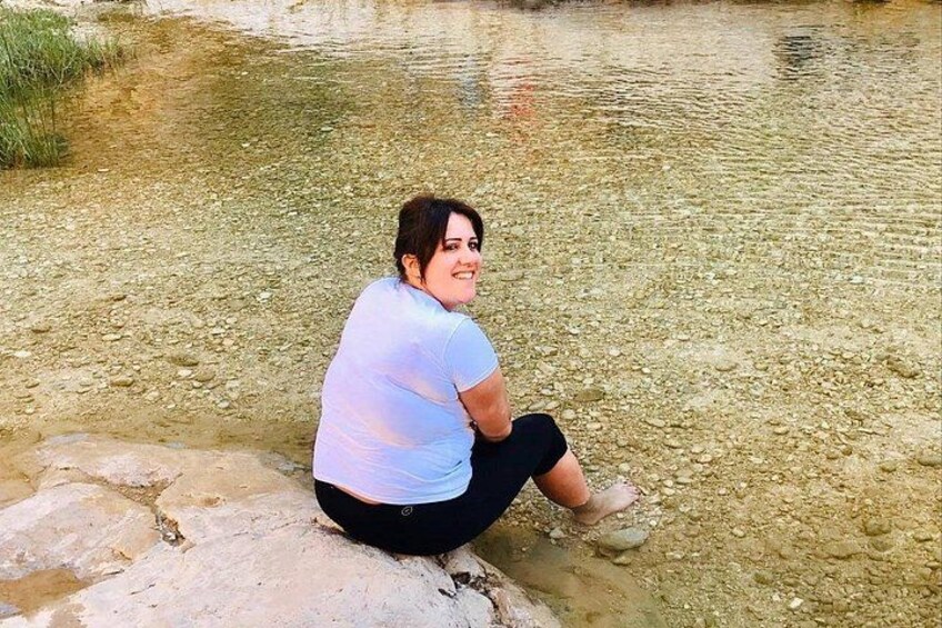 A person sitting on a rock by a clear water body. 2
