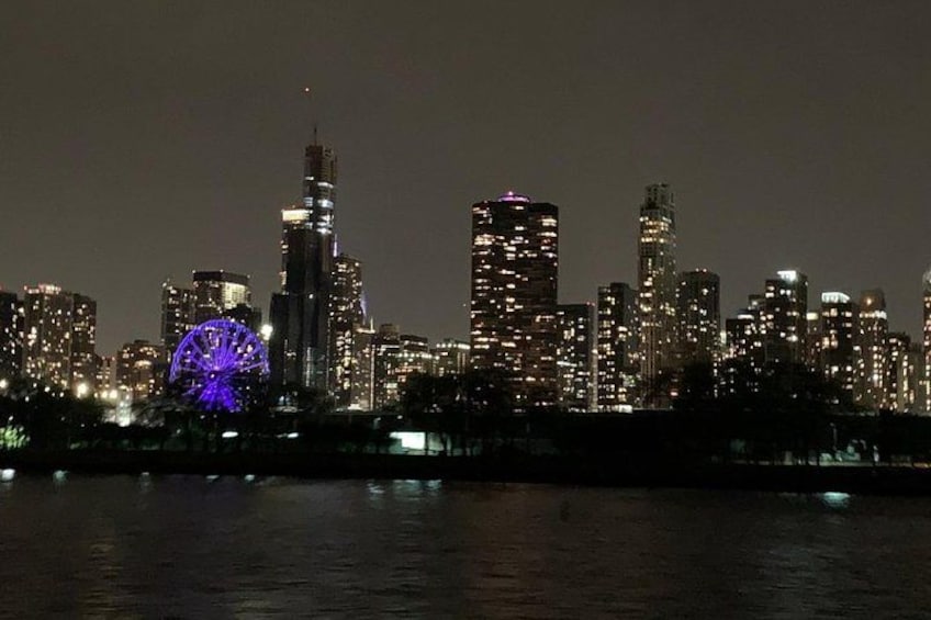 A city skyline at night with illuminated buildings and a Ferris wheel. 3